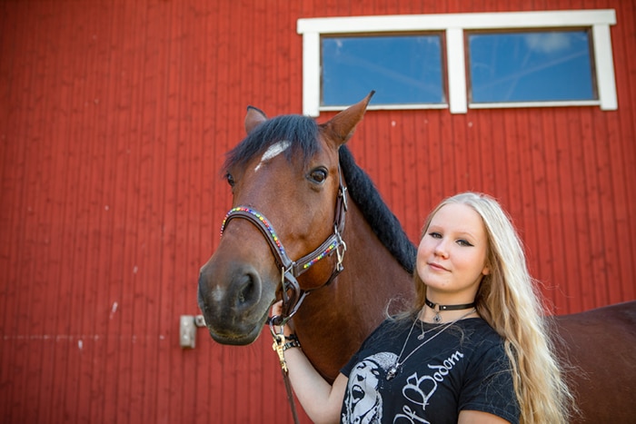 Lähikubvassa Maya ja hevonen tallin edustalla.