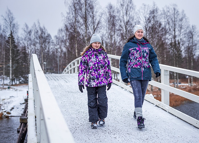 Äiti ja tytär kävelevät sillalla talvella.