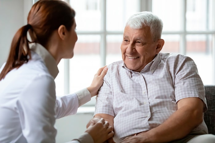 Diabeteshoitaja ja seniori-ikäinen mies istuvat sohvalla vierekkäin.