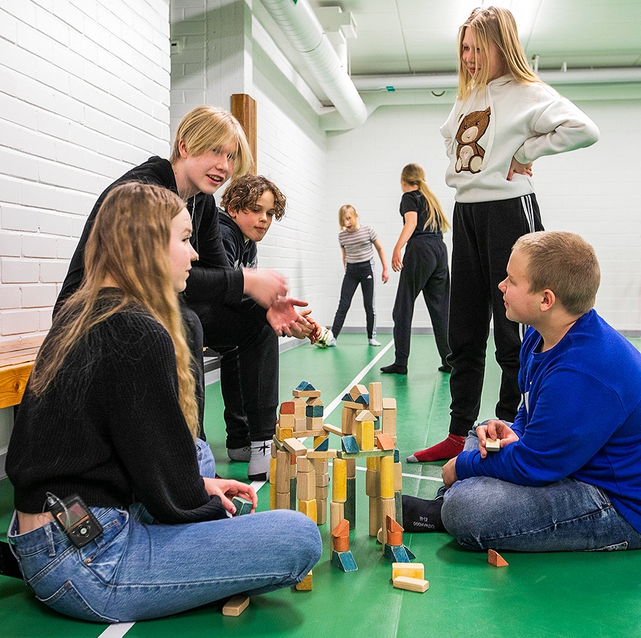 Joukko nuoria rakentavat palikoista linnaa.