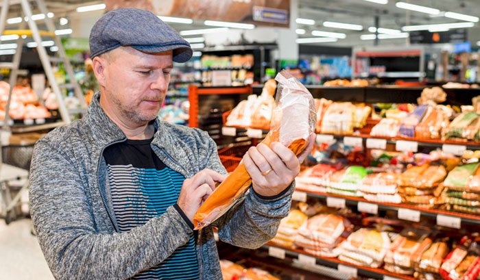 Keski-ikäinen mies tarkastelee leipäpussia ruoakkaupassa.