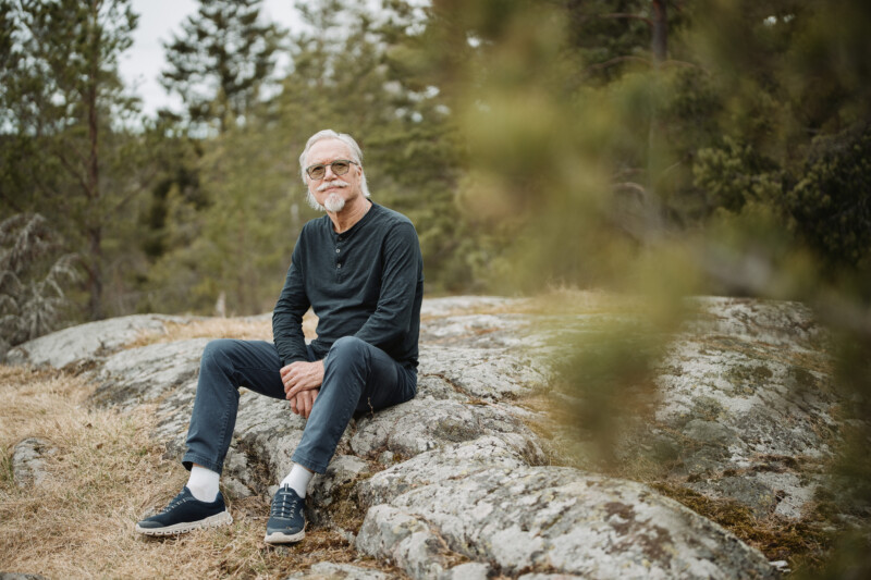 Juha Metsänoja istuu kalliolla metsässä