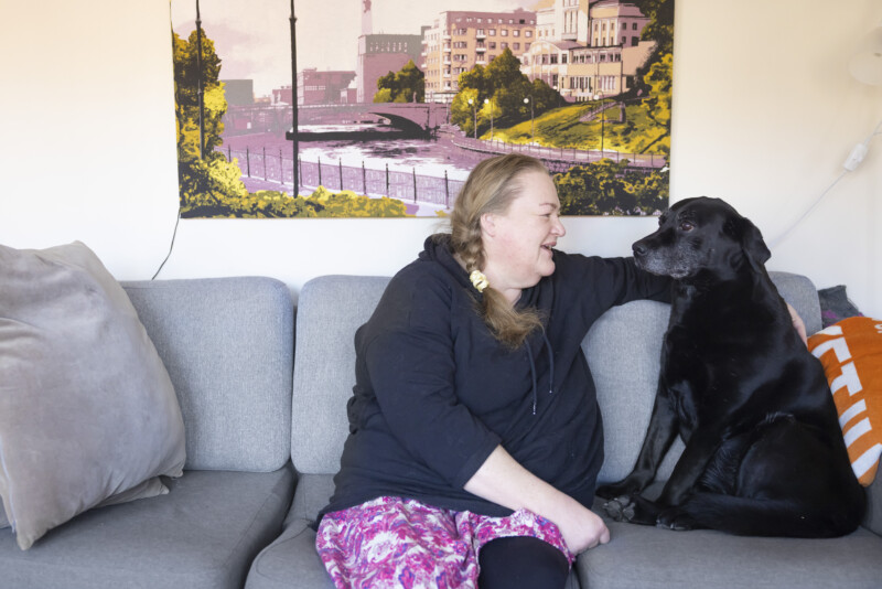 Marika Kankaanpää sohvalla Lumo-koiransa kanssa