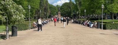 Joukko ihmisiä kävelee kesäisessä puistossa