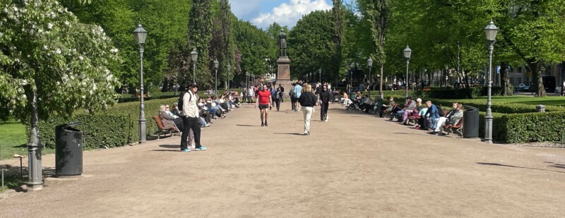 Joukko ihmisiä kävelee kesäisessä puistossa