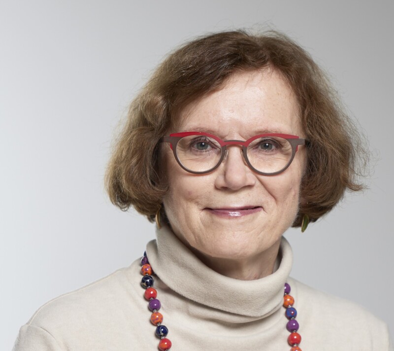 Marja Jylhän kasvokuva, Marjalla on päällään beige poolopaita ja värikäs helminauha kaulassa