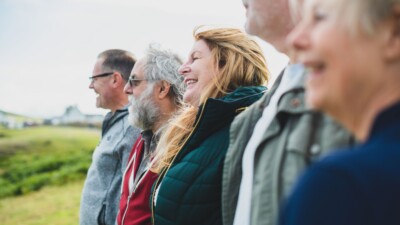 Joukko työ- ja eläkeikäisiä ihmisiä seisoo rivissä ja katsoo maisemaan